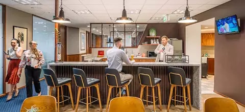Clients networking over a cup of coffee in a fully stocked kitchen.